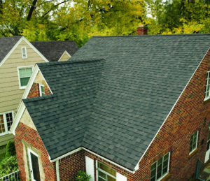 Exterior aerial view of large single family home with brick exterior and gray shingle roofing.