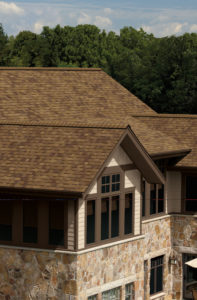 View of residence with brick exterior and brown asphalt shingle roofing.