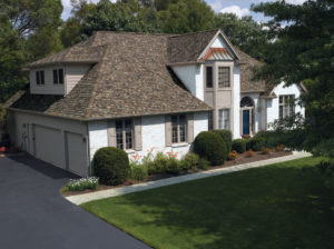 View of luxurious home with extended driveway, lush lawn, and newly installed roof.