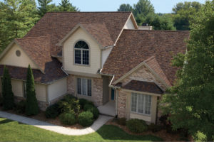 Large, two-story single family brick home with brown roofing and a long walkway.