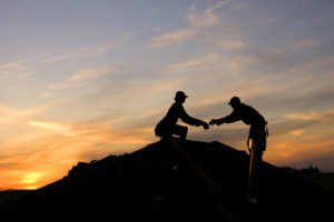 Two roofers working late on a roof top