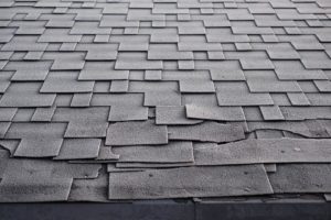 Close up view of damaged asphalt roofing shingles.
