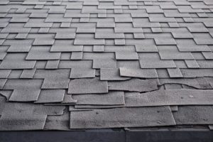 Up close view of shingle roofing damaged by wind.