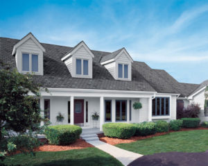 Two-story single family home with white exterior, green shrubbery, and gray asphalt shingle roofing