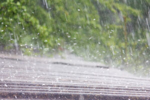 Summer rain with hail falls on a residential roof.