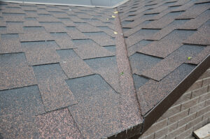 a roof valley flashing on an asphalt shingled waterproofing roofing construction of a brick house.